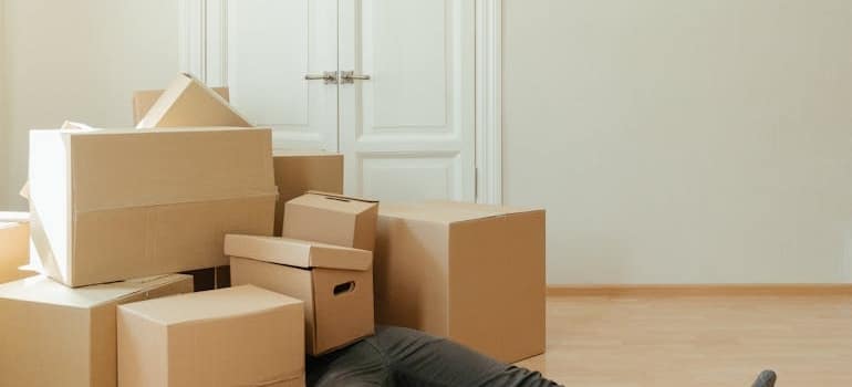 A man lying on the floor covered with boxes before renting storage in Carbondale CO