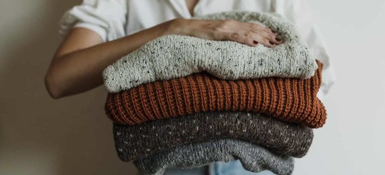 woman holding sweaters