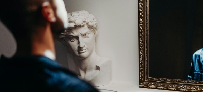 Man in Blue Shirt Standing Near White Concrete Statue thinking about hiring fine art moving services