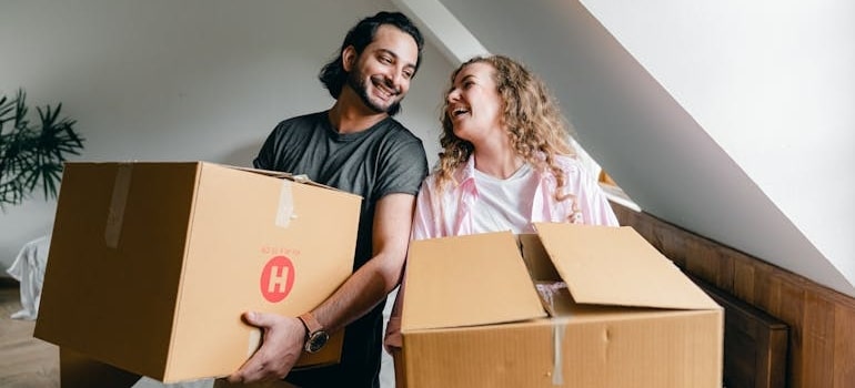 a happy couple carrying boxes