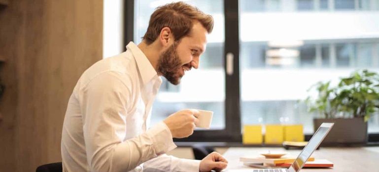 man drinking coffee and using his laptop