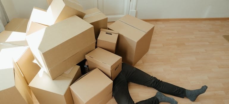 a man under a pile of boxes before clearing out the attic