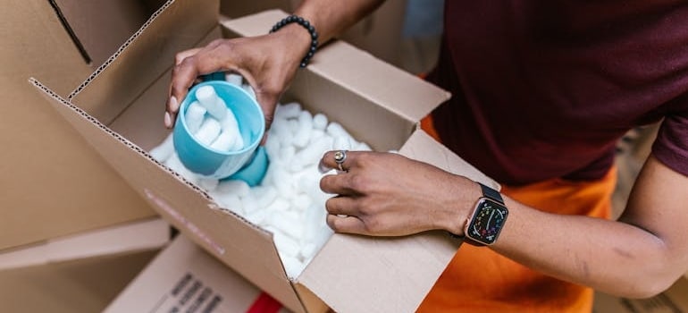a man storing fragile items in a box full f packing peanuts