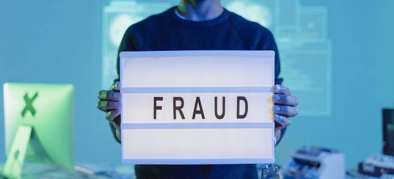 a person holding a lamp with 'fraud' written on it
